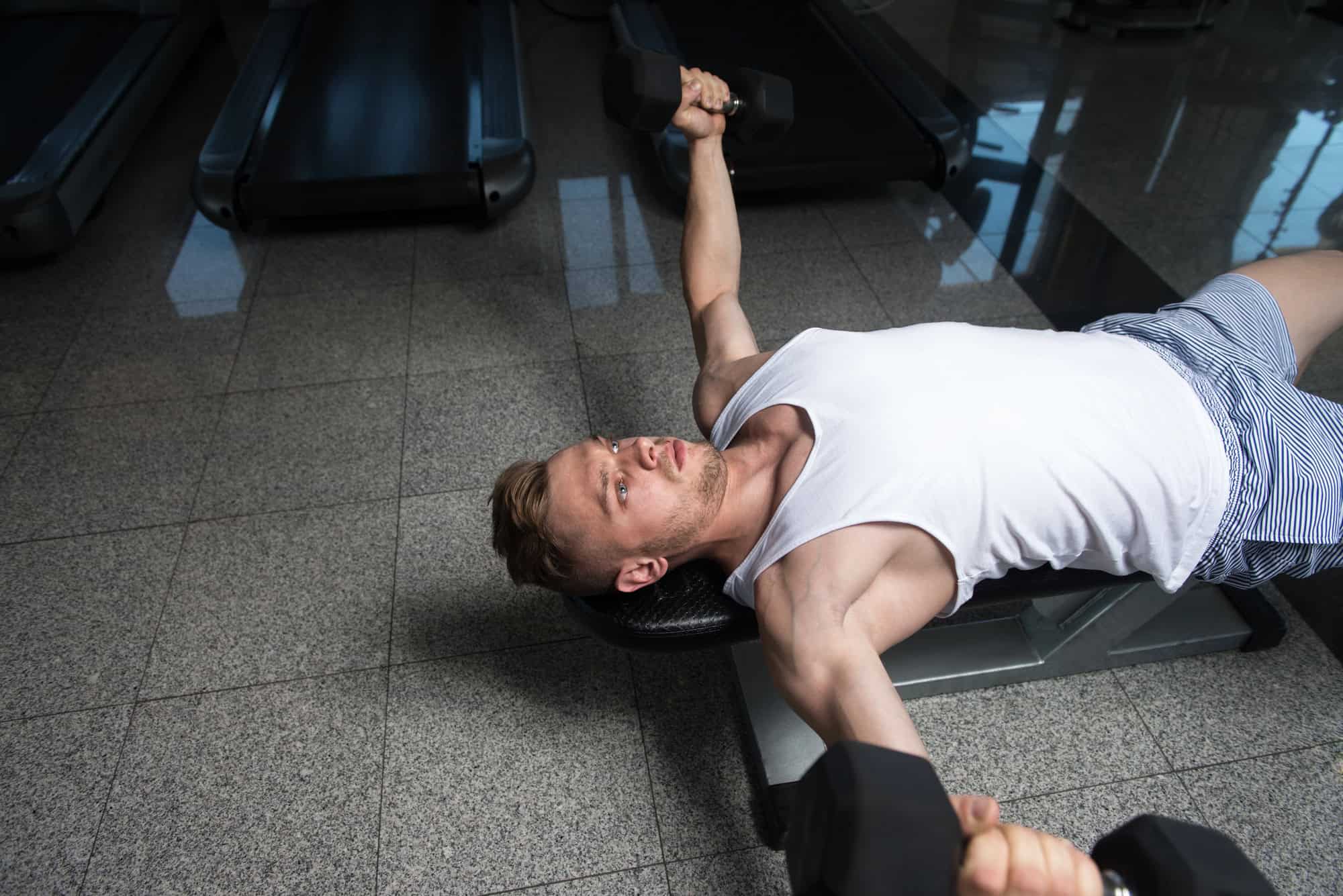 Chest Workout – Dumbbell Chest Fly for Muscle Isolation Man lying on a bench performing a dumbbell chest fly as part of a 6 day gym workout schedule to isolate and strengthen chest muscles