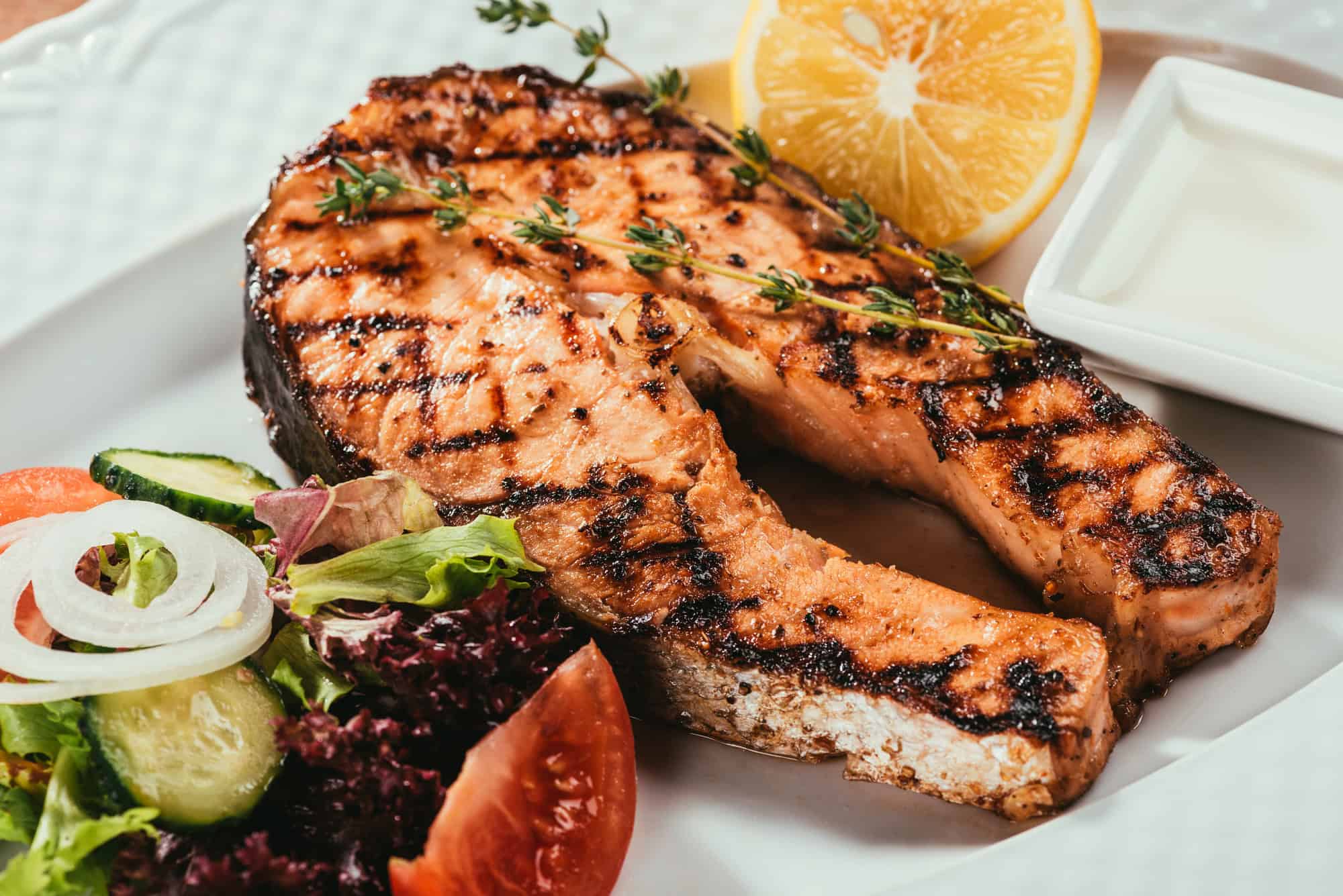 Grilled salmon fillet served with fresh salad and lemon for a high protein low calorie meal
