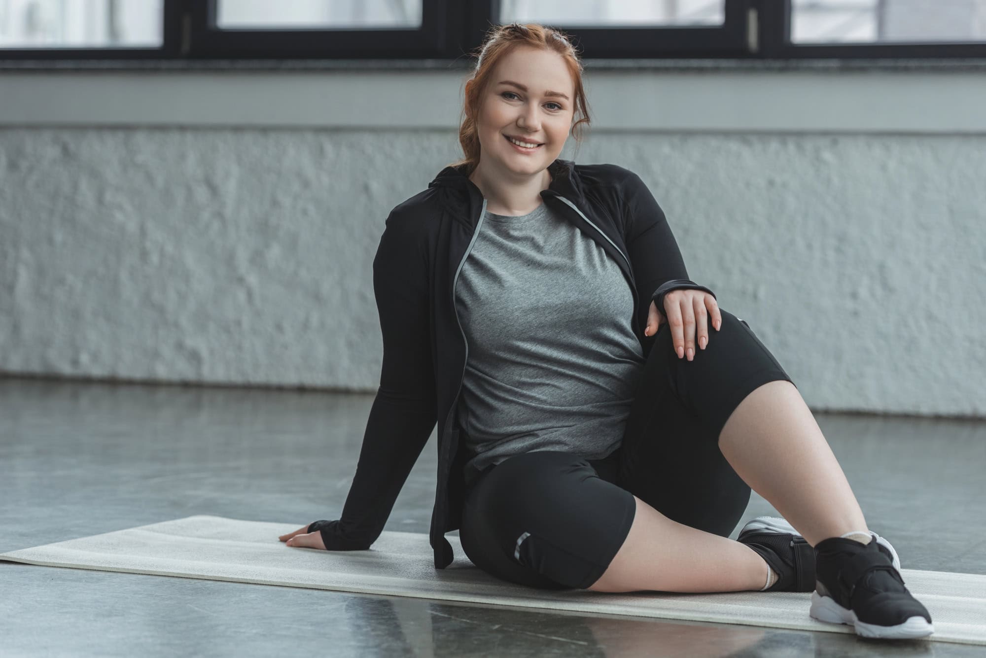 Smiling woman resting on a mat after completing a female beginner workout plan session