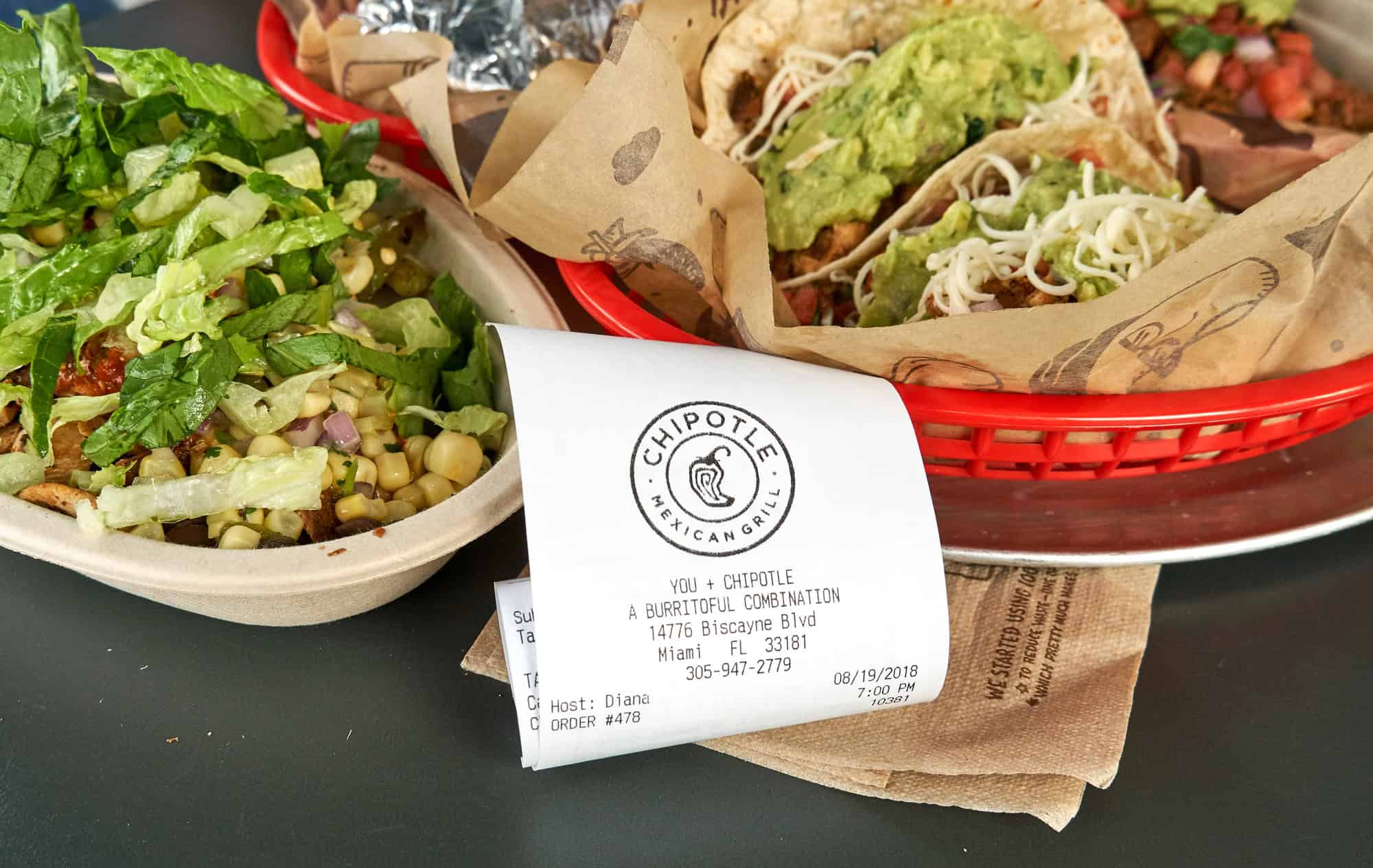 Chipotle burrito bowl and tacos with a printed receipt, representing convenient high protein ready meals
