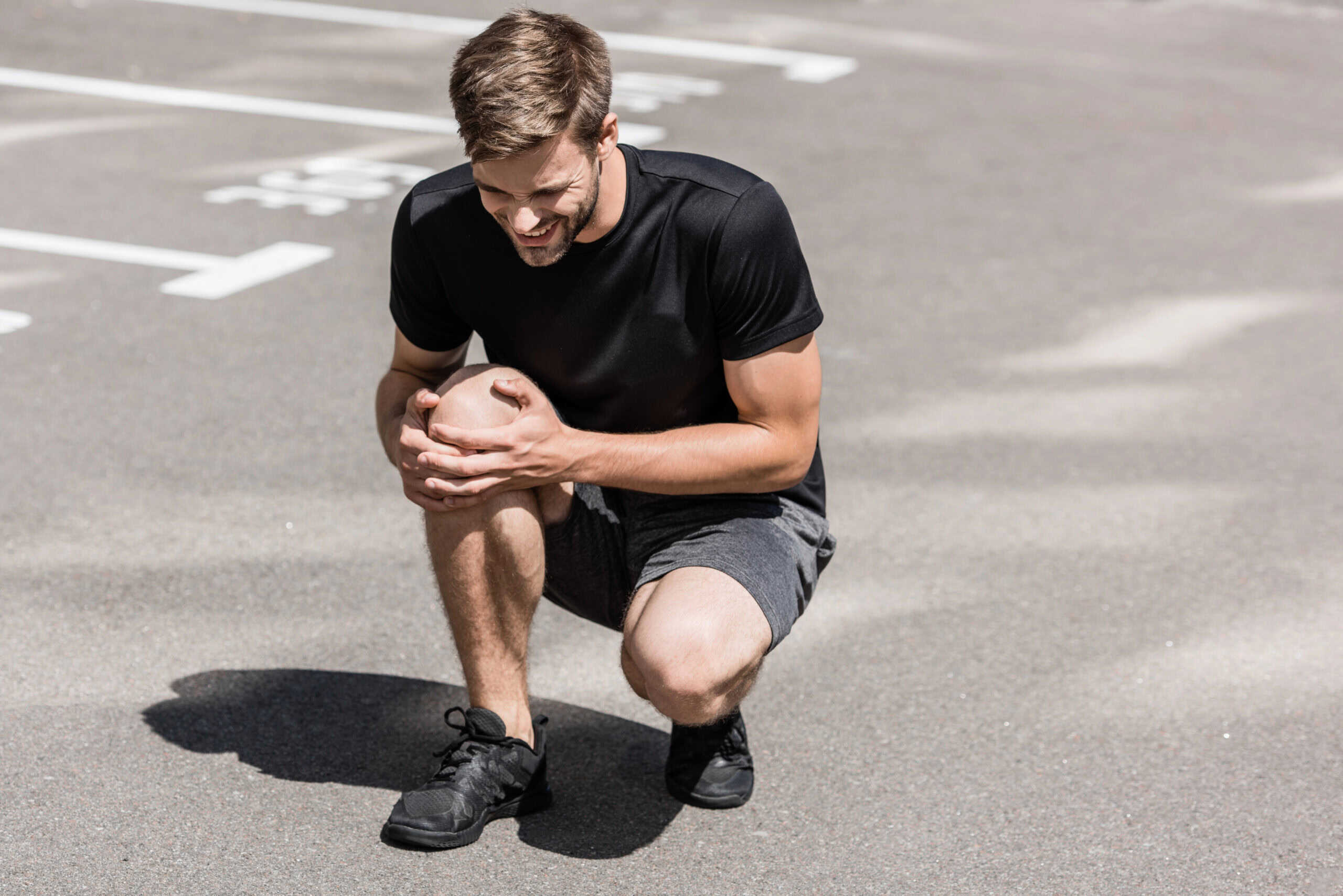 Man holding his knee in pain - How to start working out again after knee injury
