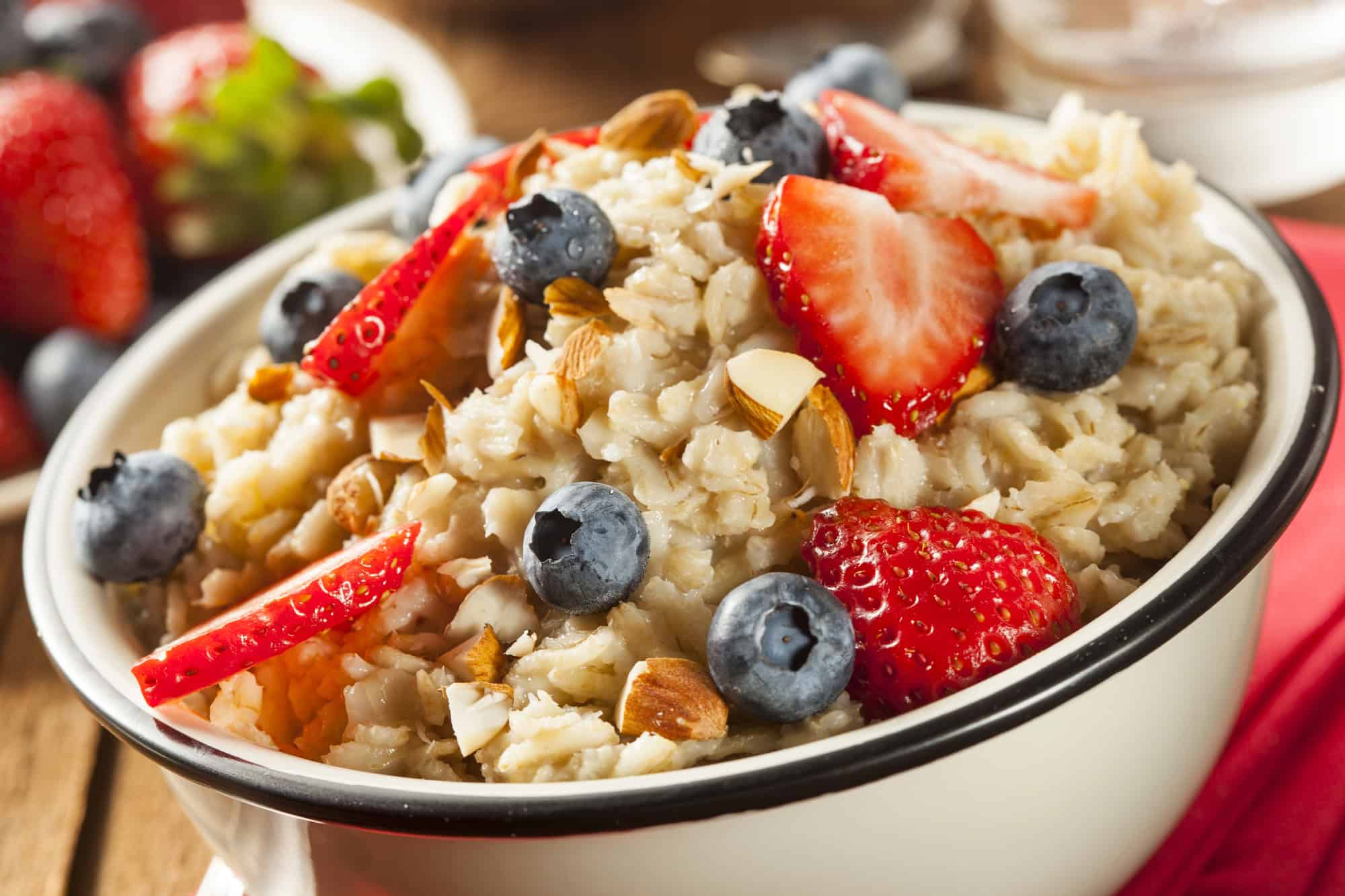 High Protein Vegan Meals – Oatmeal with Berries and Almonds Bowl of oatmeal topped with strawberries, blueberries, and almonds as a high protein vegan meal breakfast option