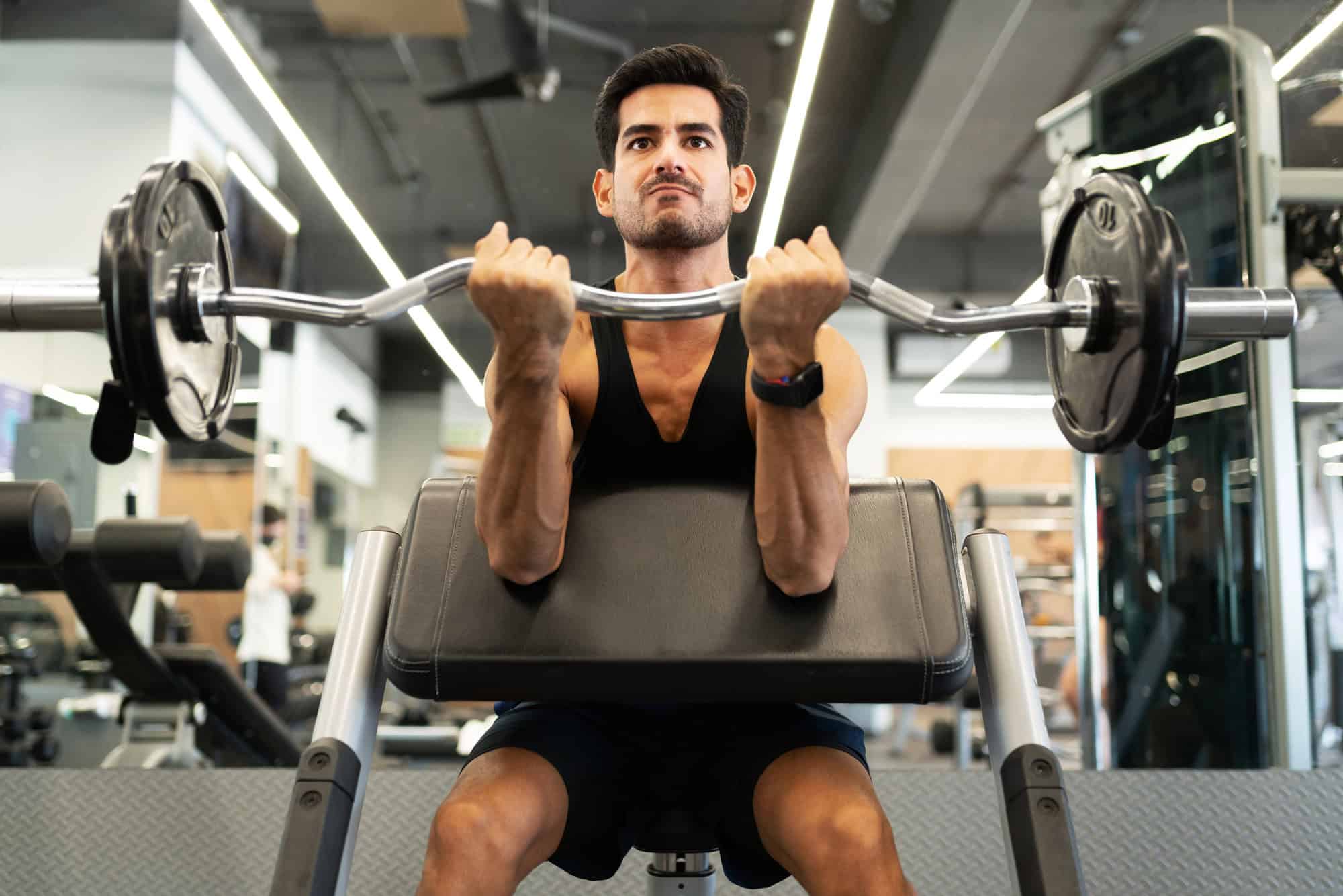 Man doing preacher curls with an EZ bar for biceps isolation in an arm training routine