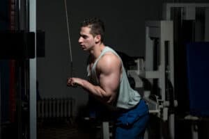 Man doing cable triceps pushdowns during a gym-based triceps workout for muscle definition