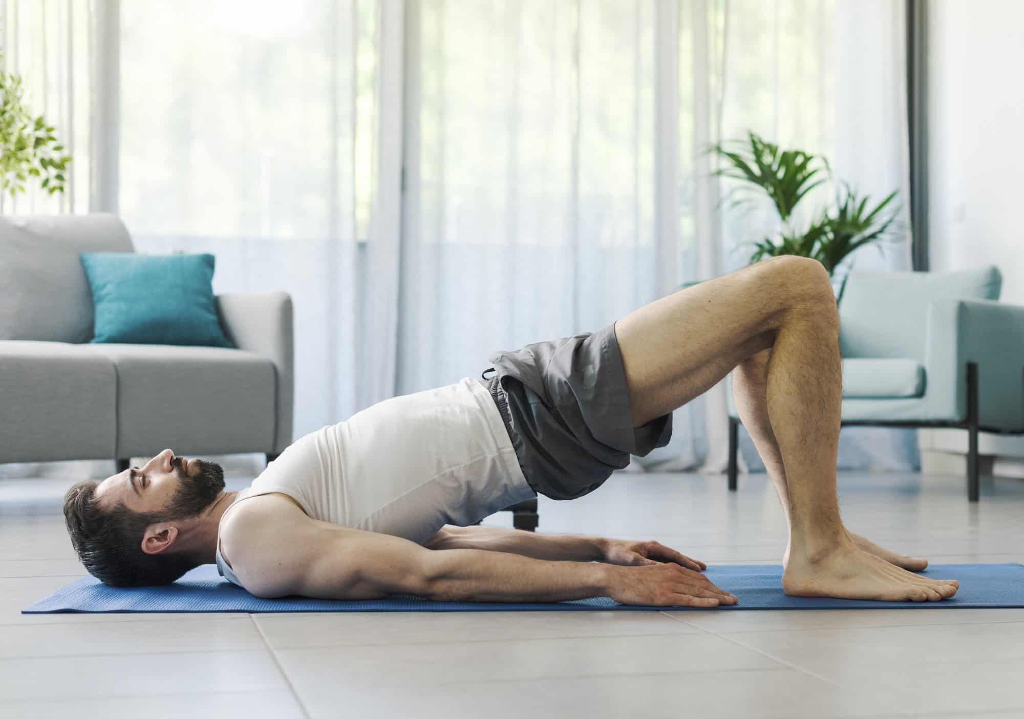 Bodyweight Leg Workout – Glute Bridges for Hamstrings and Glutes Man lying on a mat doing glute bridges to target the lower body