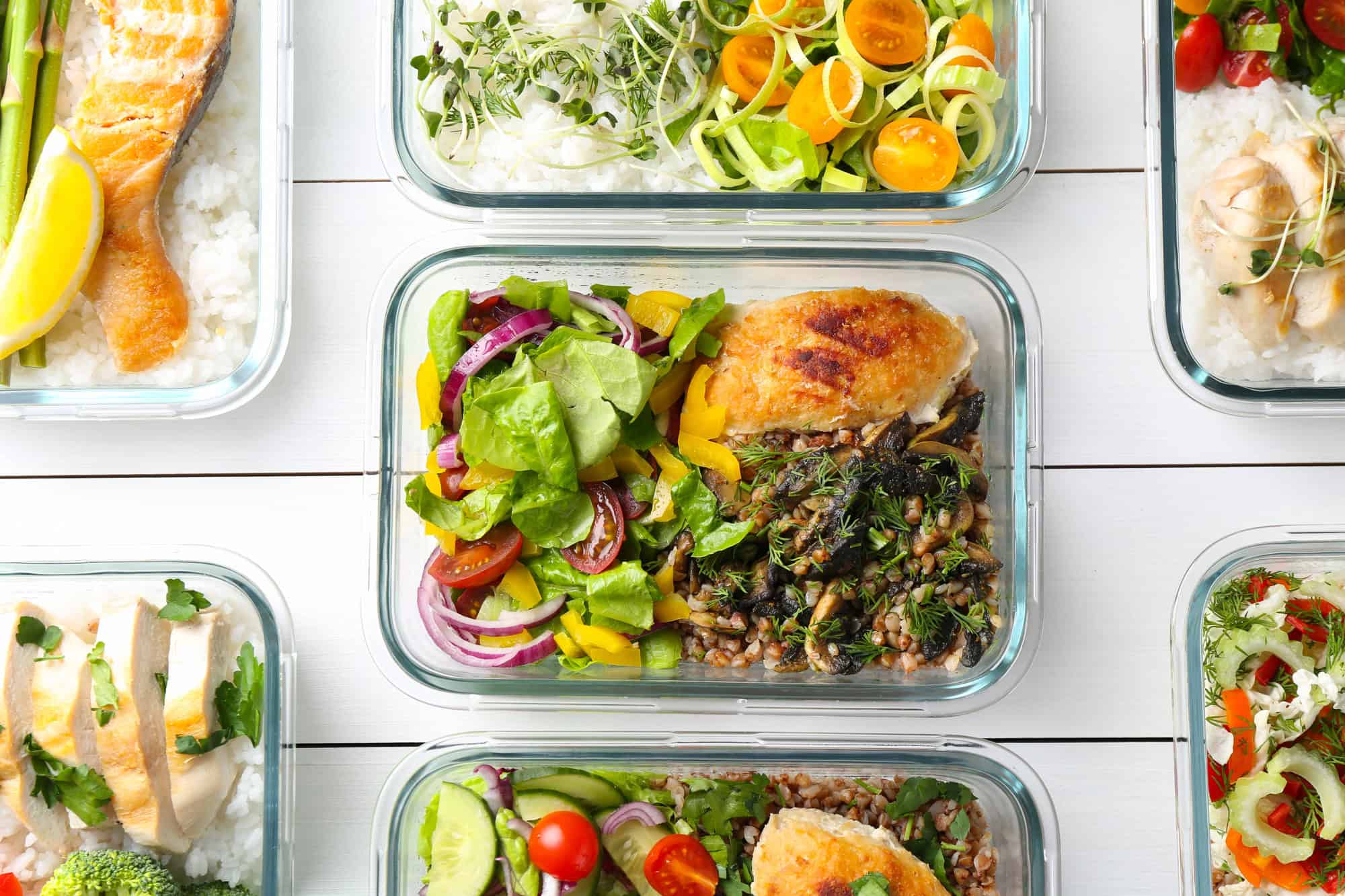 Multiple meal prep containers with chicken, grains, and vegetables as part of an easy high protein meal prep routine